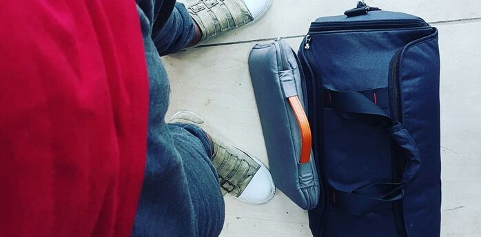 Traveller standing beside cabin suitcase and personal bag