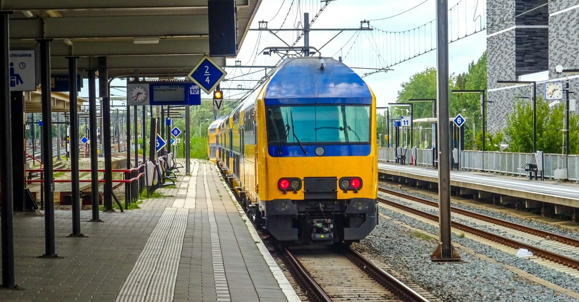 Yellow and blue passenger train standing at a railway platform in Europe