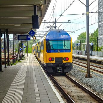 Yellow and blue passenger train standing at a railway platform in Europe