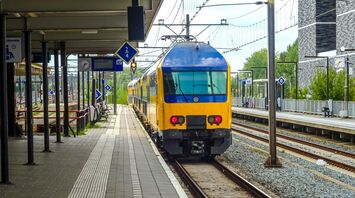 Yellow and blue passenger train standing at a railway platform in Europe