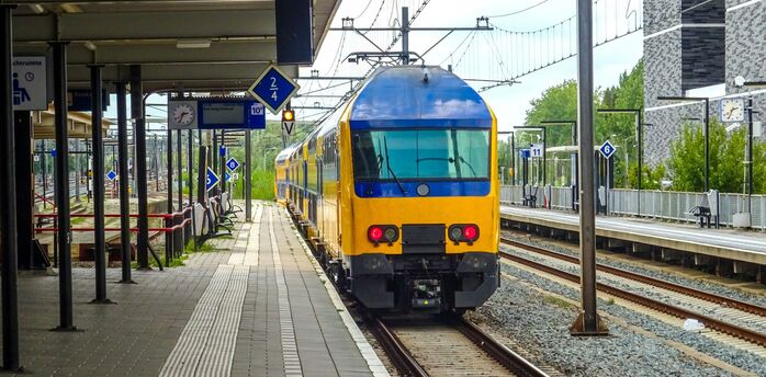 Yellow and blue passenger train standing at a railway platform in Europe
