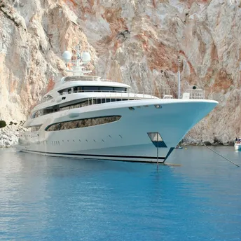 Luxury yacht anchored near rocky coastal cliffs and clear water