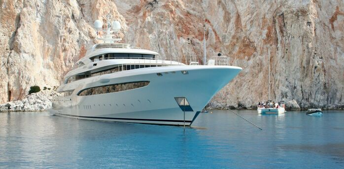 Luxury yacht anchored near rocky coastal cliffs and clear water