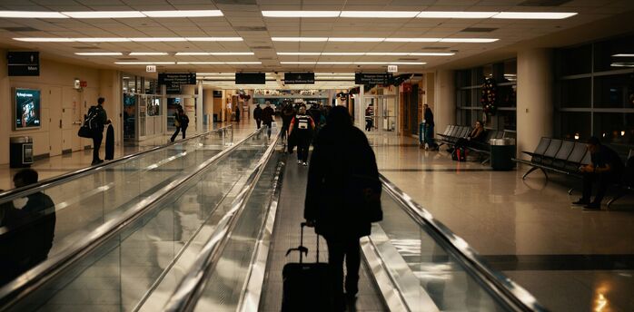 Passenger walking through airport corridor with rolling suitcase