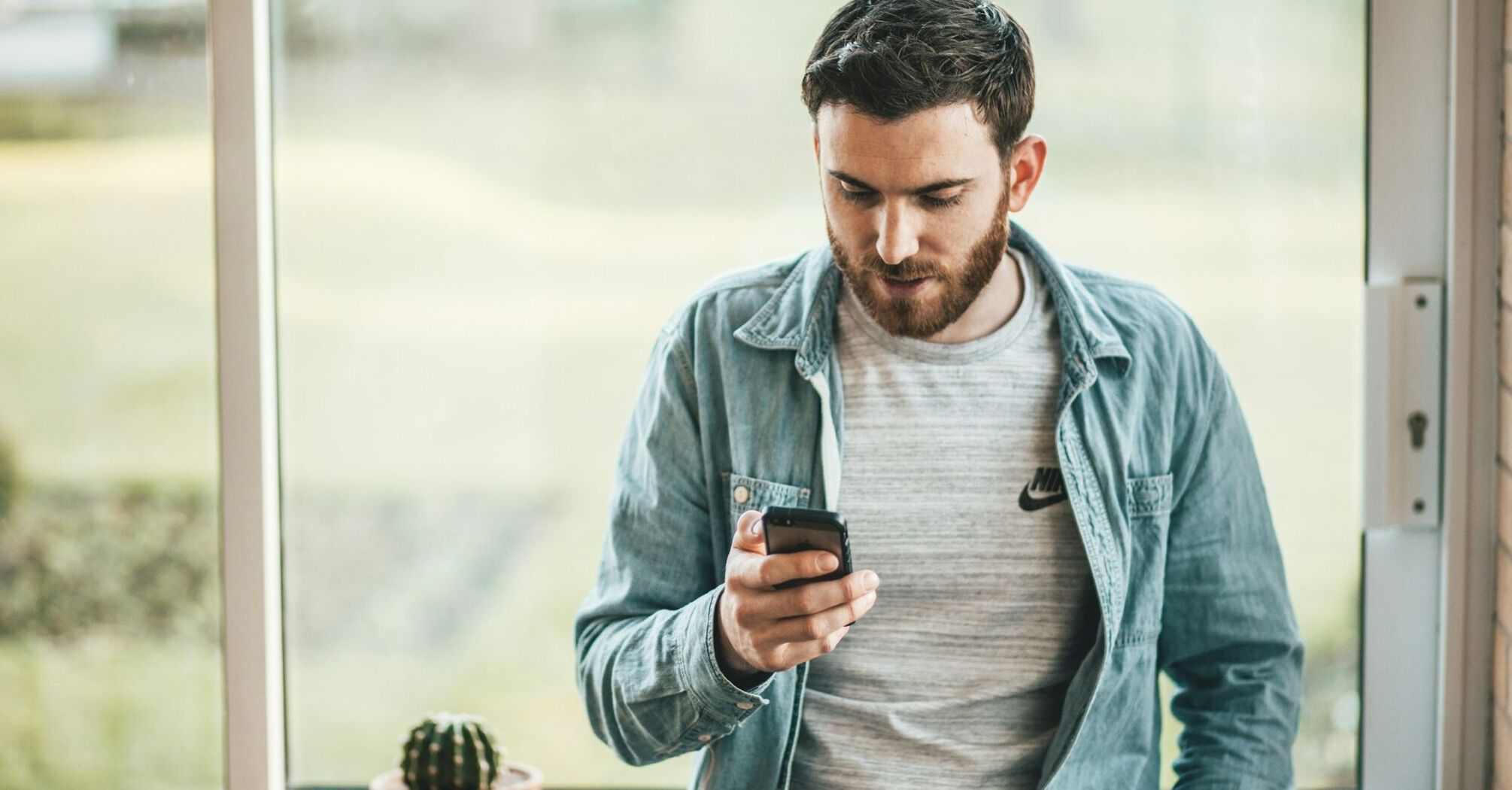 Man checking travel details on smartphone near window