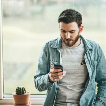 Man checking travel details on smartphone near window
