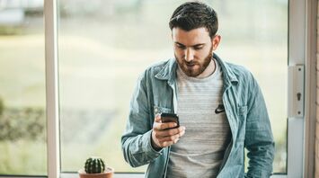 Man checking travel details on smartphone near window