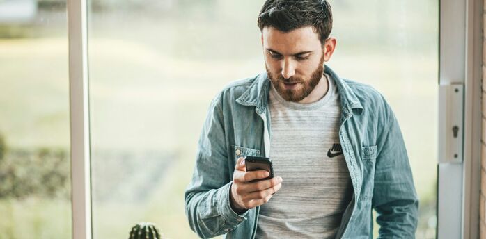 Man checking travel details on smartphone near window