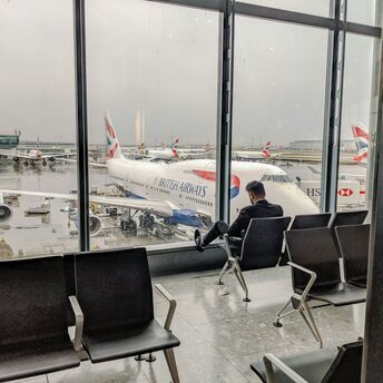 Passenger waiting at Heathrow terminal overlooking British Airways aircraft