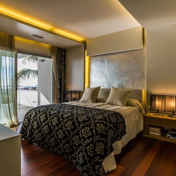 Modern hotel bedroom with balcony and warm lighting