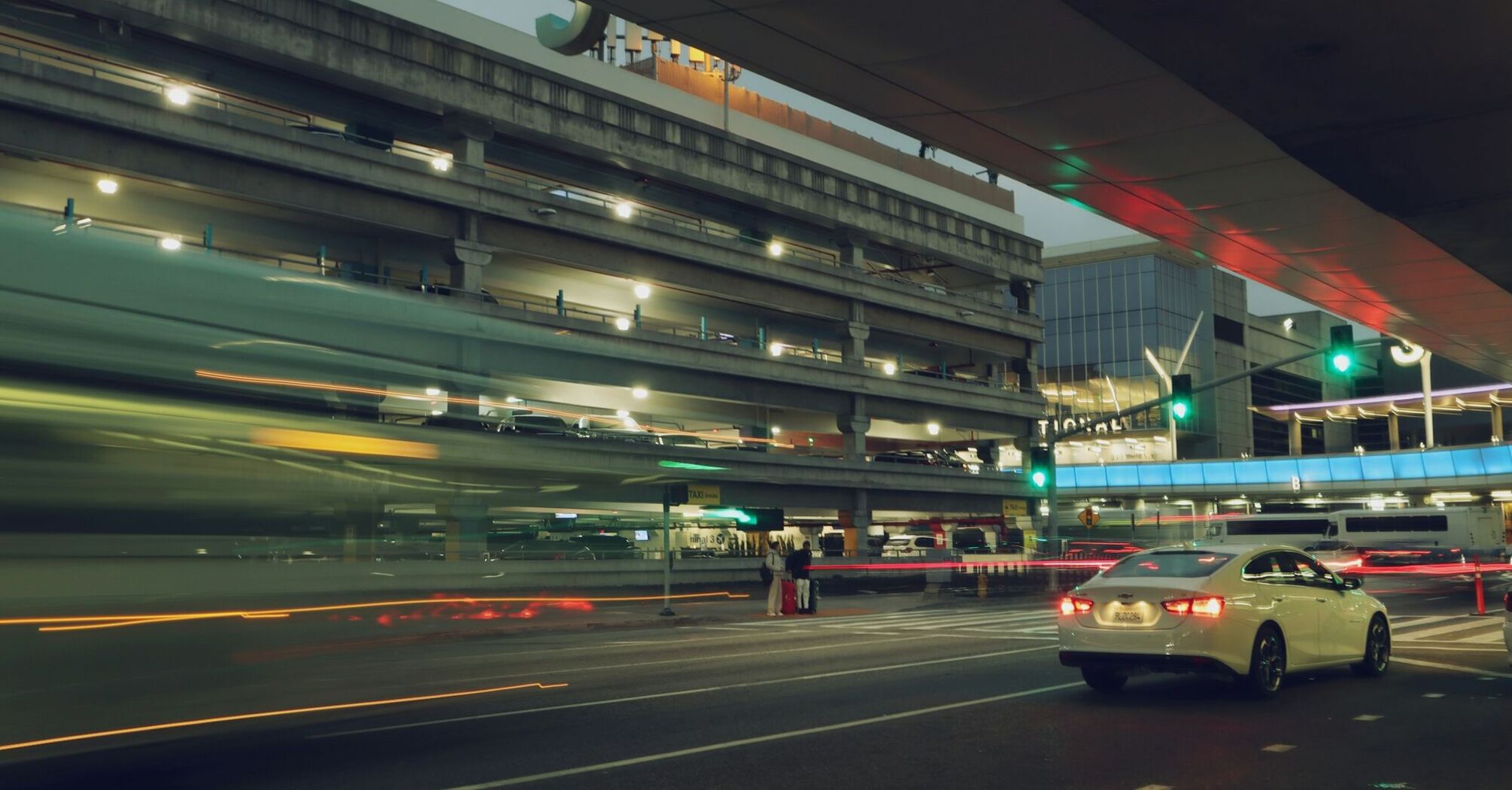 Cars passing through airport terminal drop-off area at night