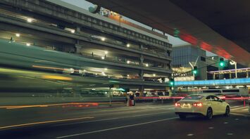 Cars passing through airport terminal drop-off area at night