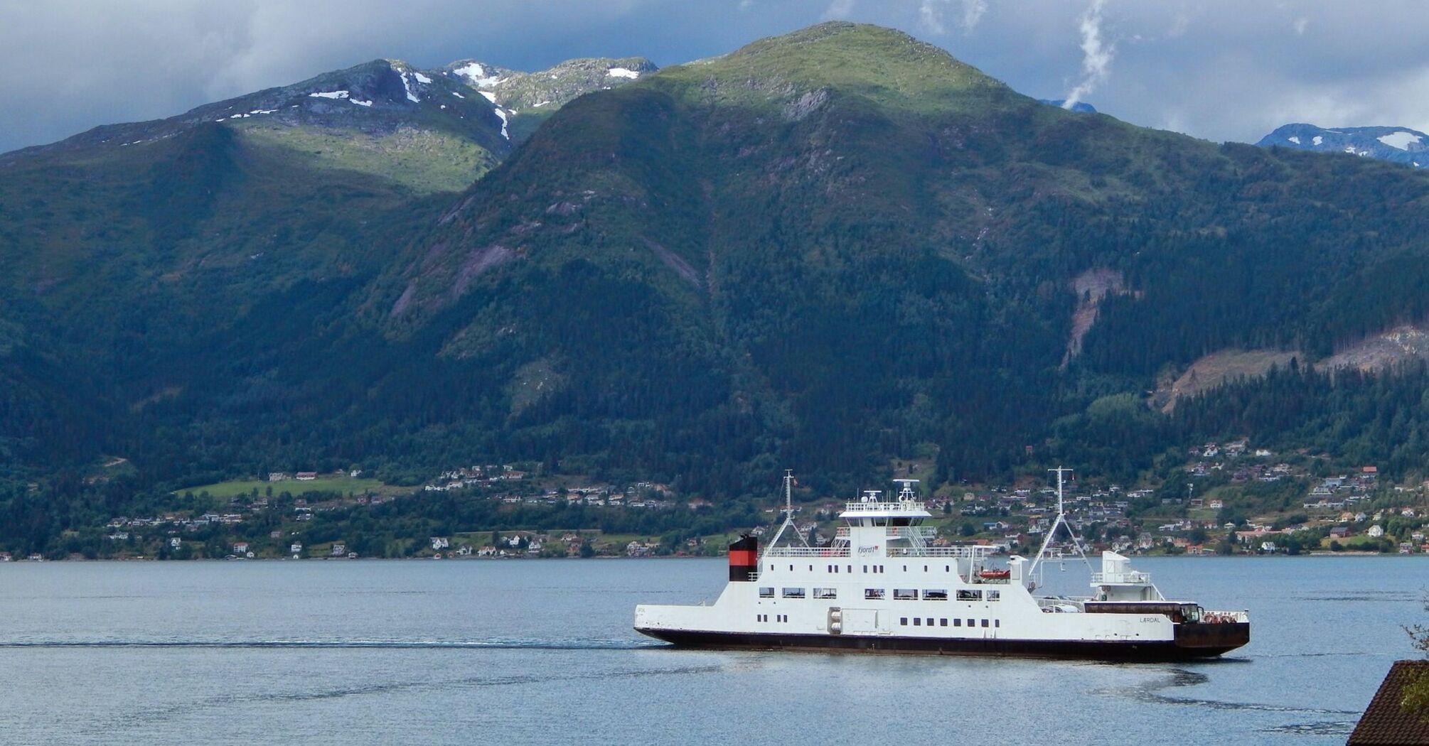 Ferry sailing along Norwegian fjord mountains