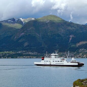 Ferry sailing along Norwegian fjord mountains