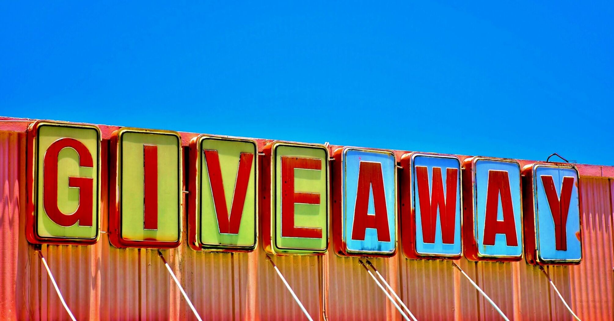 Colourful giveaway sign against blue sky
