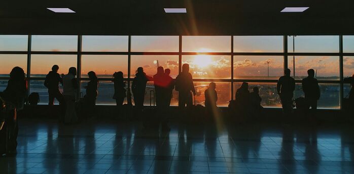 Passengers waiting inside airport terminal at sunset