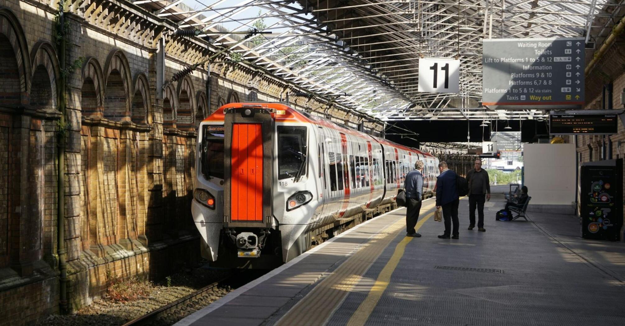 Train at British railway station platform with passengers waiting