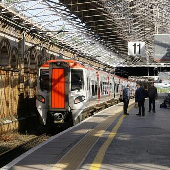 Train at British railway station platform with passengers waiting