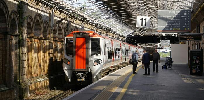 Train at British railway station platform with passengers waiting