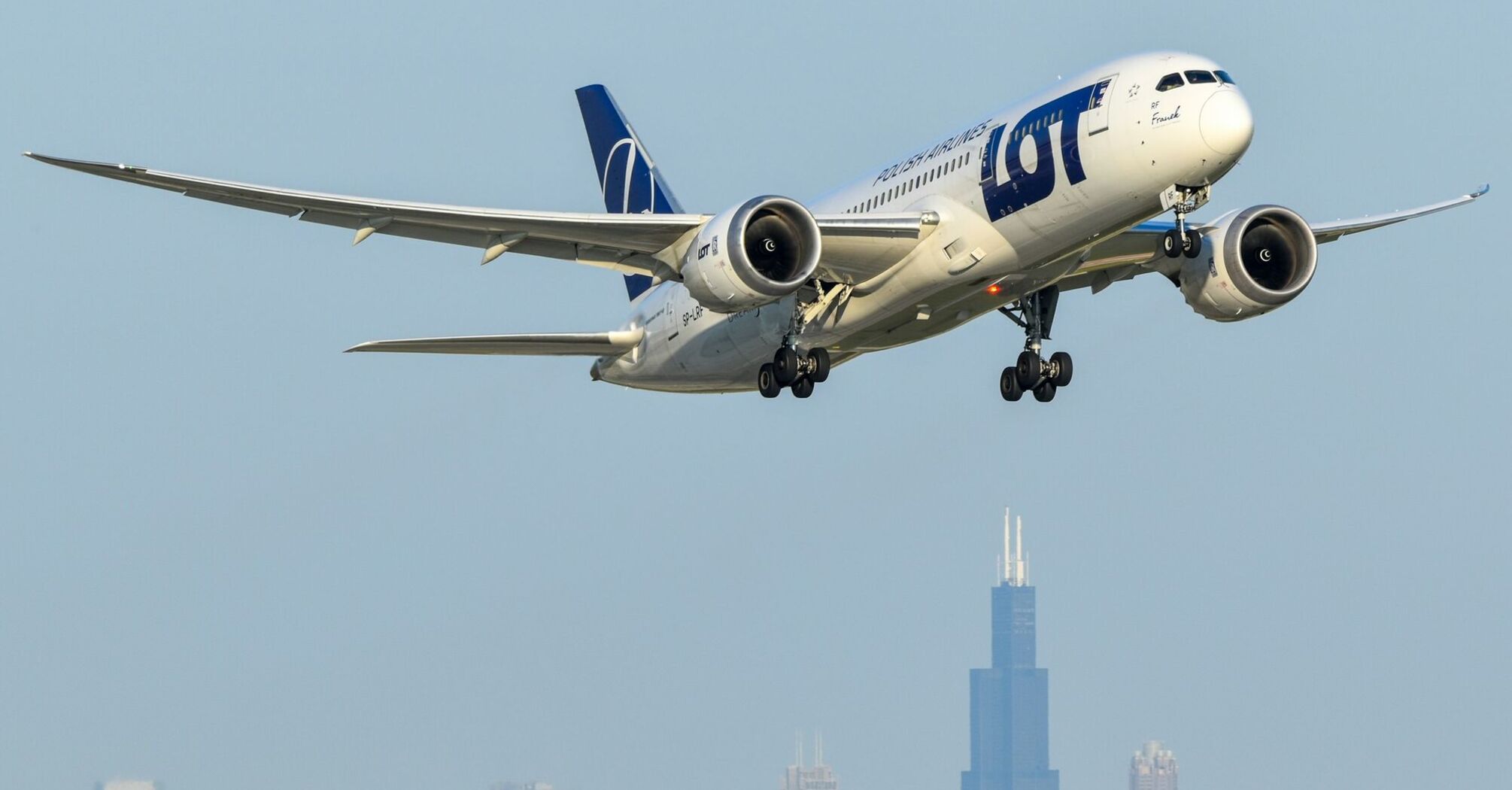 LOT Polish Airlines aircraft approaching city skyline