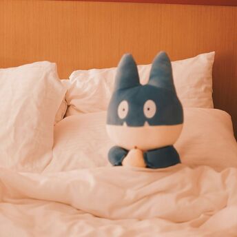 Plush toy sitting on a hotel bed