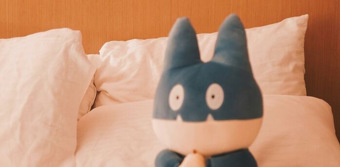 Plush toy sitting on a hotel bed