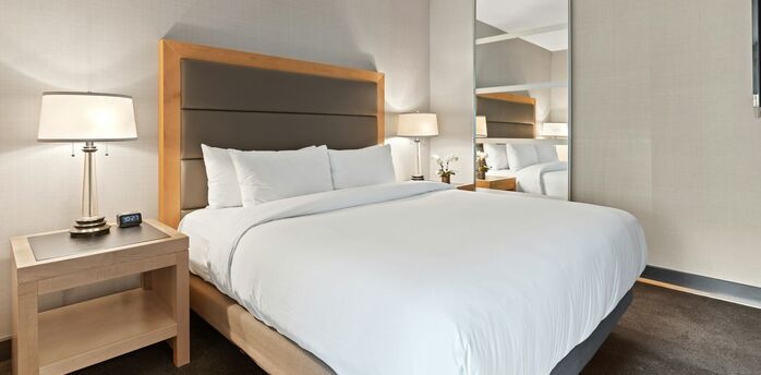 Modern minimalist hotel bedroom with large bed and mirrored wardrobe