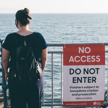 Woman standing near a “No Access” sign by the sea