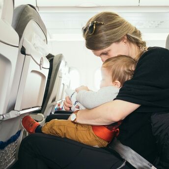 Parent holding baby on lap during airplane flight