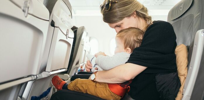 Parent holding baby on lap during airplane flight