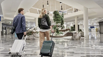 Passengers walking through Helsinki Airport terminal with Nordic-style interior design and greenery