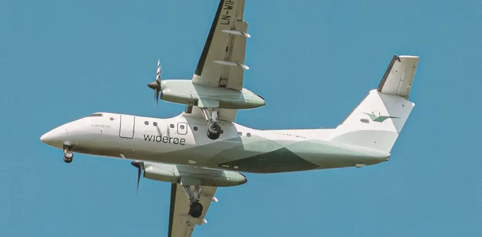 Widerøe turboprop aircraft in flight against blue sky