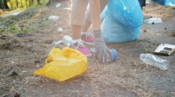 Person picking up plastic waste outdoors with gloves