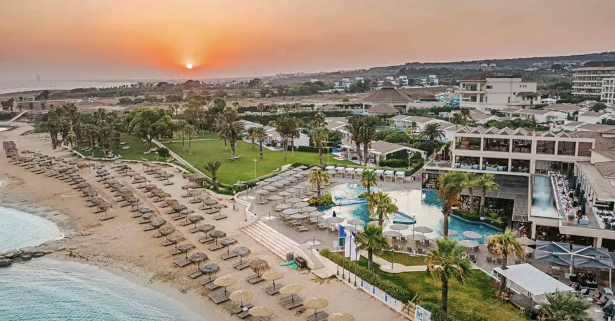 Beachfront resort with pools, sunbeds and sunset coastline view in Cyprus