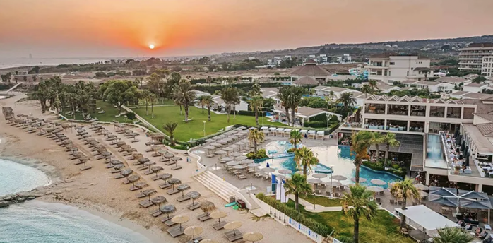 Beachfront resort with pools, sunbeds and sunset coastline view in Cyprus
