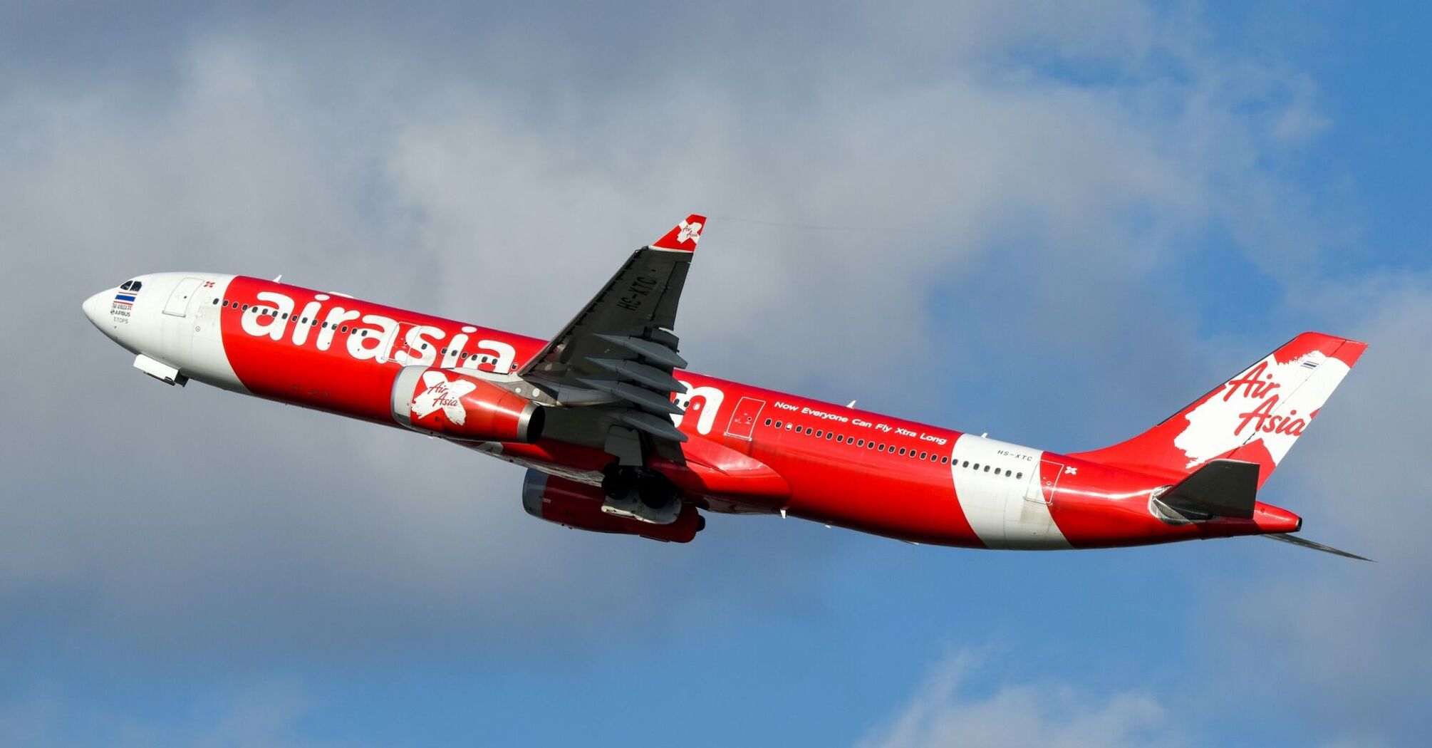 AirAsia aircraft in red livery flying in blue sky