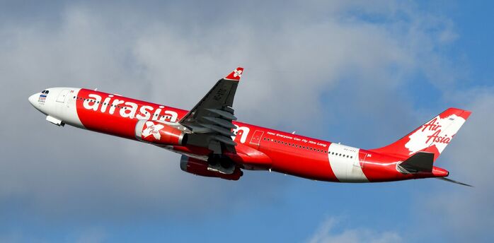 AirAsia aircraft in red livery flying in blue sky