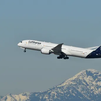 Lufthansa aircraft taking off with mountains in background