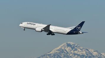 Lufthansa aircraft taking off with mountains in background