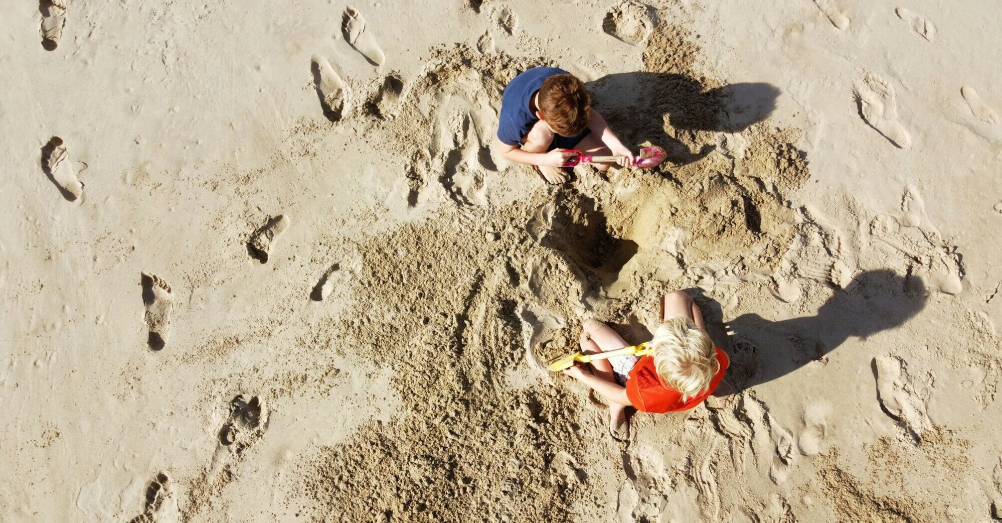 Children digging sand with buckets and spades on beach