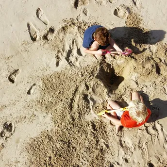 Children digging sand with buckets and spades on beach