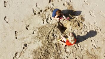 Children digging sand with buckets and spades on beach