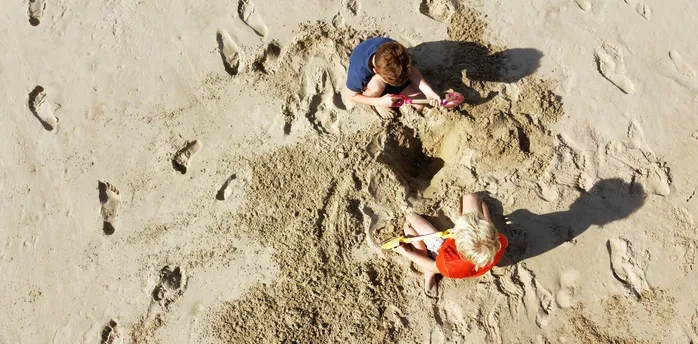Children digging sand with buckets and spades on beach