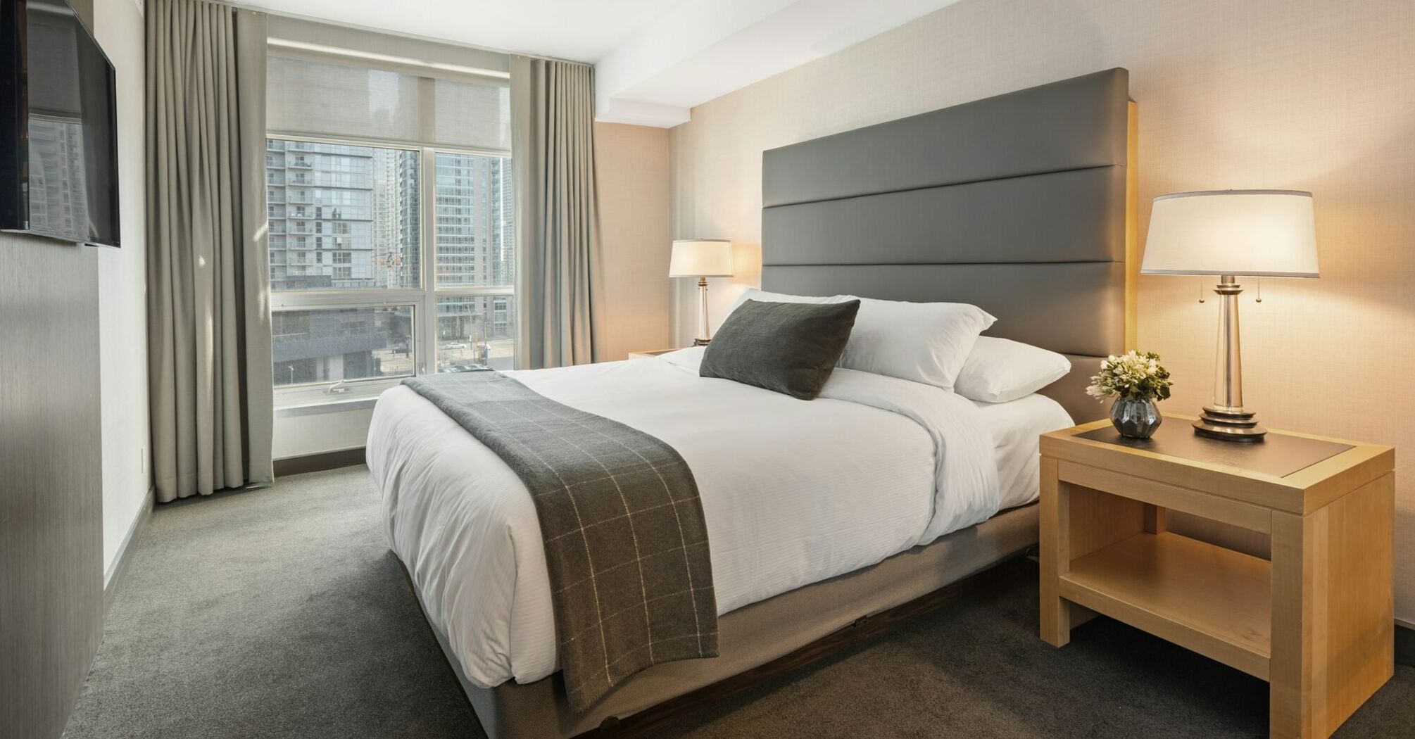 Modern hotel bedroom with large bed and city view window