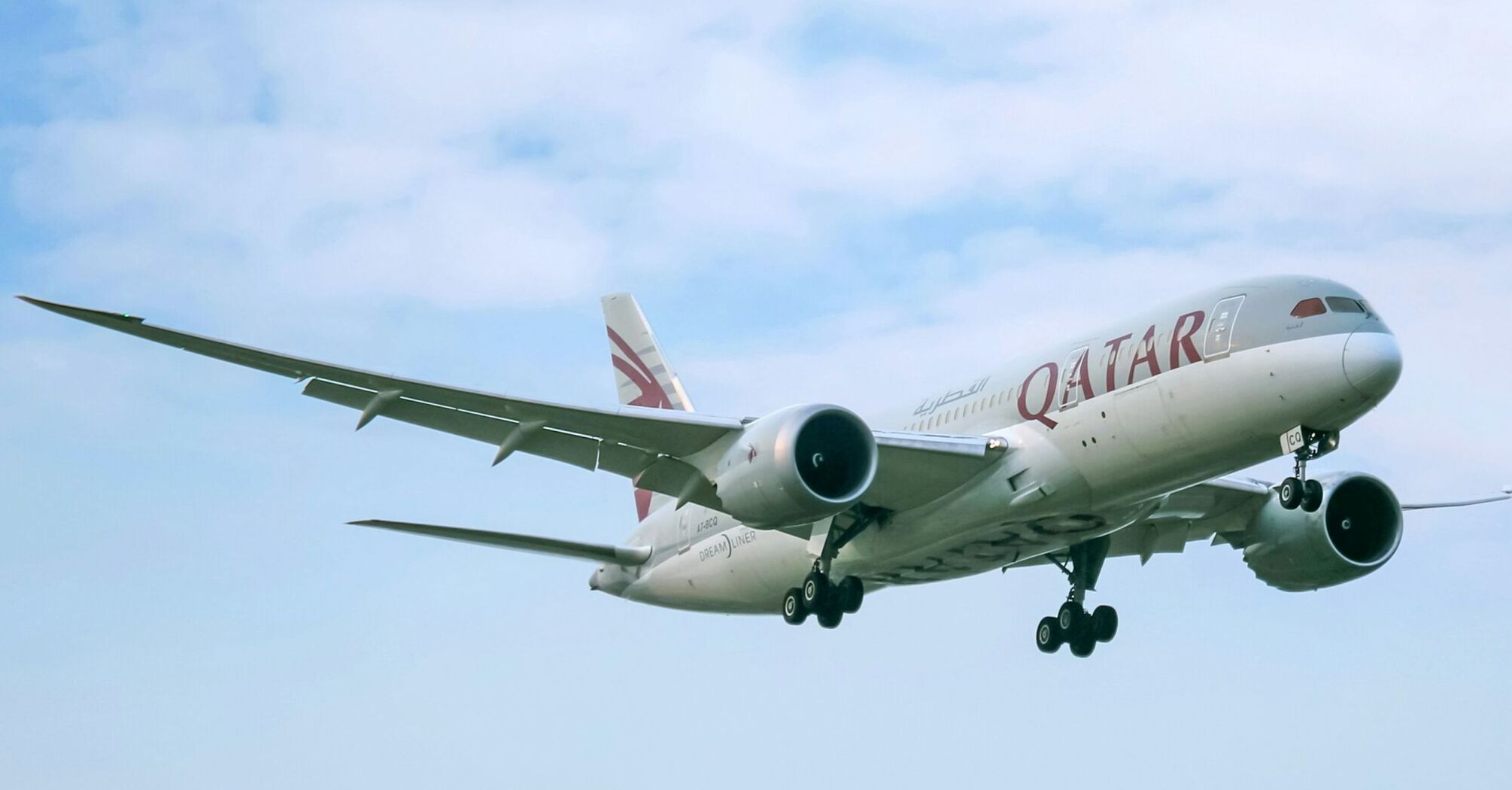 Qatar Airways aircraft in flight against cloudy sky