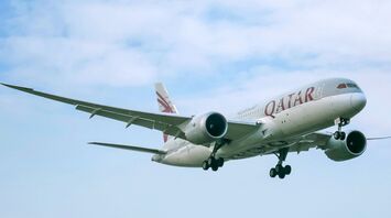 Qatar Airways aircraft in flight against cloudy sky