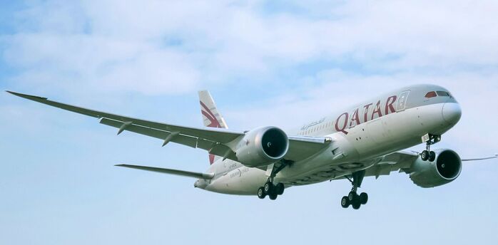 Qatar Airways aircraft in flight against cloudy sky