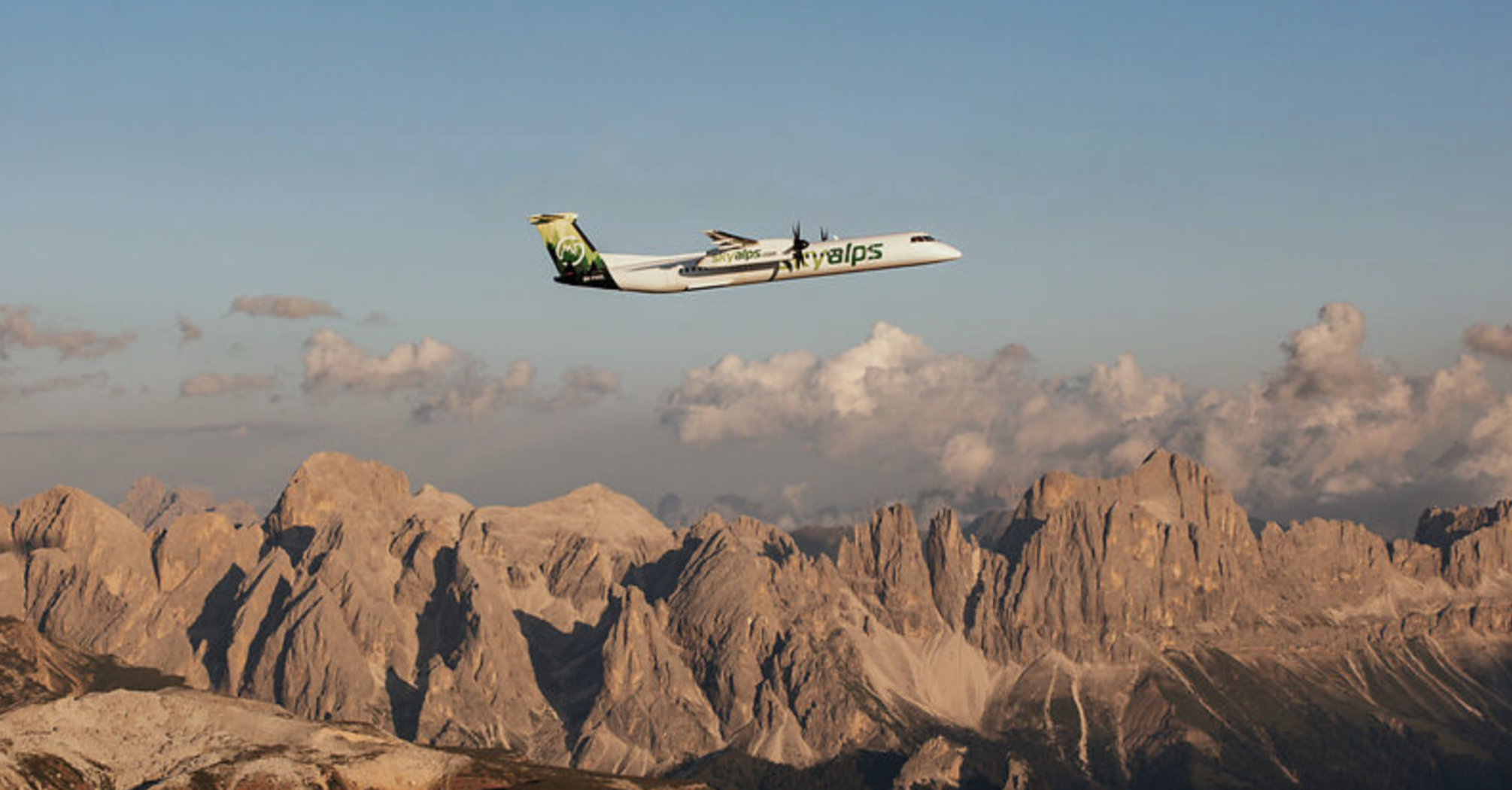 SkyAlps aircraft flying over Alpine mountain landscape