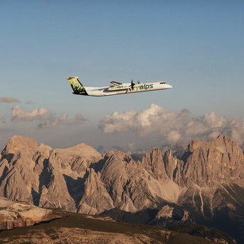 SkyAlps aircraft flying over Alpine mountain landscape