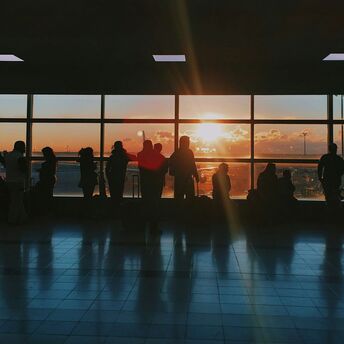Silhouettes of travellers waiting inside an airport terminal at sunset